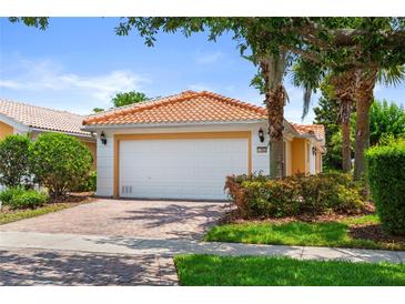 Charming single-story home featuring a red tile roof, lush landscaping, and a brick-paved driveway at 11863 Delfina Ln, Orlando, FL 32827