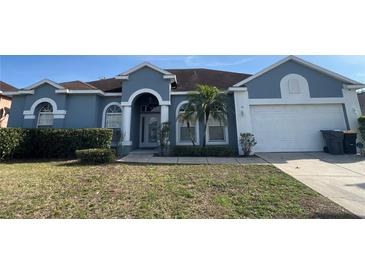 Charming single-story home with a well-manicured lawn, arched entryway, and attached two-car garage at 151 Prestwick Dr, Davenport, FL 33897