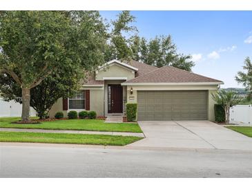 Charming single-story home with a well-manicured lawn, mature tree, and a two-car garage at 2950 Inca Ave, Clermont, FL 34715