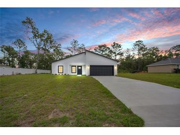 New construction home with dark grey accents, black garage door and green grass in the yard at 357 Marion Oaks Pass, Ocala, FL 34473