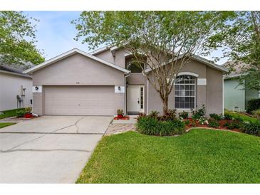 Charming single-Gathering home with a well-maintained lawn, flowering shrubs, and a two-car garage at 516 Brett Ct, Orlando, FL 32828