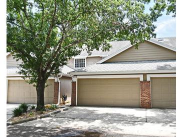 Inviting townhouse with neutral siding, attached garages, brick accents, and mature trees shading the facade at 677 Post Oak Cir # 115, Altamonte Springs, FL 32701