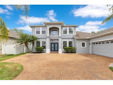 Stunning two-story home featuring a brick driveway, lush landscaping, and a welcoming double-door entrance at 8676 Currituck Sound Ln, Orlando, FL 32829