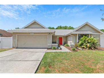 Charming single-story home with a well-maintained lawn, two-car garage, and a vibrant red front door at 10124 Pink Carnation Ct, Orlando, FL 32825