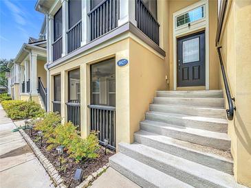 Inviting two-story townhome exterior with black railings, tan stucco, and landscaped front yard at 1027 Cedar Bay Ln, Winter Springs, FL 32708