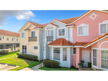 Colorful townhouses featuring tile roofs, manicured lawns, and decorative architectural details at 1201 S Beach Cir, Kissimmee, FL 34746