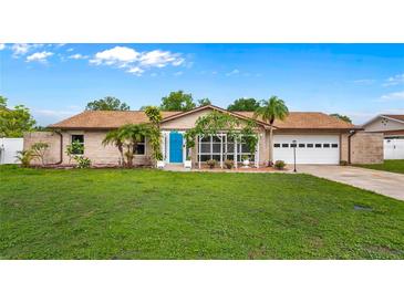 Charming single-story home with a bright blue door, lush lawn, and mature landscaping at 2316 Irlo Dr, Kissimmee, FL 34741