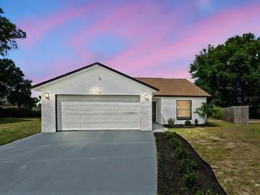 Charming single-story home with a white exterior, complemented by a two-car garage and a well-manicured lawn at 274 W 20Th St, Apopka, FL 32703