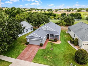 Charming home featuring a brick driveway, manicured lawn, and a golf course view, perfect for relaxed living at 3008 Pinnacle Ct, Clermont, FL 34711