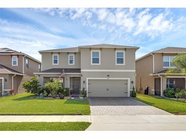 Charming two-story home with a manicured lawn and a brick-paved driveway leading to a two-car garage at 455 Lazio Cir, Debary, FL 32713
