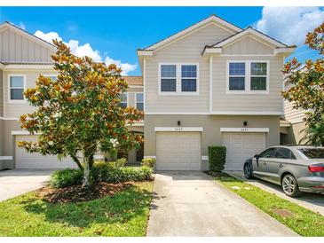 Two-story townhome with a well-maintained lawn, lush landscaping, and private garage and driveway at 9069 Shepton St, Orlando, FL 32825
