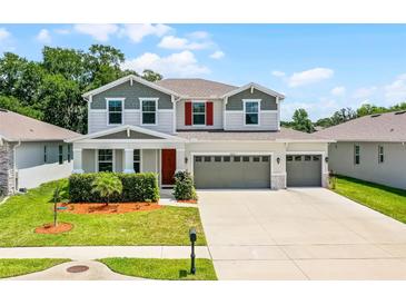 Two-story home with a three car garage, landscaped front yard, gray trim, and red shutters at 10249 Spring Lake Dr, Clermont, FL 34711