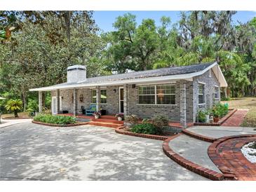 Charming single-story brick home featuring a cozy front porch and well-manicured landscaping at 1090 Braddock Rd, Deltona, FL 32725