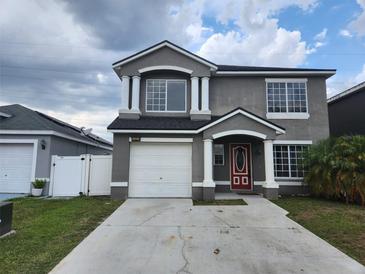 Charming two-story home with a red front door, well-manicured lawn and a private two-car garage at 1321 Carey Glen Cir, Orlando, FL 32824