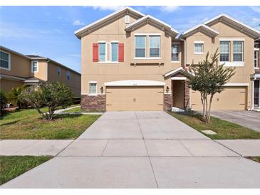 Two story home with a two car garage, stone accents, tan exterior paint and red shutters at 1610 Mohegan Blvd, Kissimmee, FL 34744