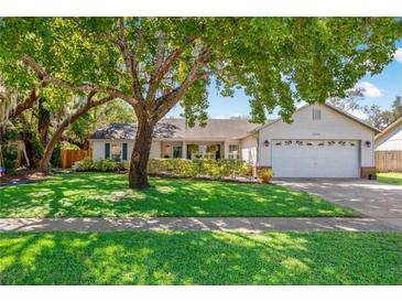 Charming single-story home featuring a lush green lawn, mature trees, and a welcoming two-car garage at 4235 Shades Crest Ln, Sanford, FL 32773