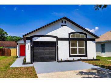 Charming one-story home featuring a black garage door and a red front door at 6856 Ebans Bend, Orlando, FL 32807