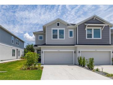 Charming townhome featuring a two-car garage, manicured landscaping, and stylish gray exterior at 1915 Terrapin Rd, Ocoee, FL 34761