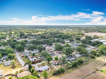 Expansive aerial view of a neighborhood with mature trees and clear blue skies at 2571 Edmond Cir, Auburndale, FL 33823