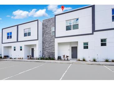 Modern townhome exterior with clean lines, gray accents, and ample parking space for residents and visitors at 348 Famagusta Dr, Davenport, FL 33896