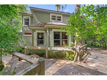 Two-story home with wood deck, surrounded by lush greenery and mature trees in a secluded setting at 4107 Gabriella Ln, Winter Park, FL 32792