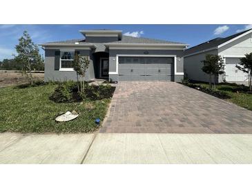 Charming single-Gathering home features a gray exterior, a two-car garage and a brick paver driveway at 5262 Teirgarten St, St Cloud, FL 34771