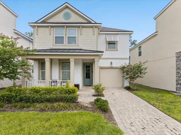 Charming two-story home featuring a well-maintained lawn and a beautiful brick driveway leading to an attached garage at 8943 Coconut Breeze Dr, Kissimmee, FL 34747