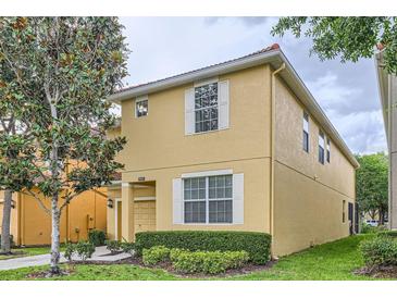 Two story home boasts a yellow exterior, white trim, and a well-manicured lawn at 8989 Cuban Palm Rd, Kissimmee, FL 34747