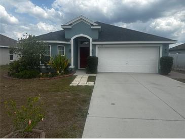Inviting single-story home featuring a well-manicured lawn and a convenient two-car garage at 1185 Sabine Ln, Kissimmee, FL 34759