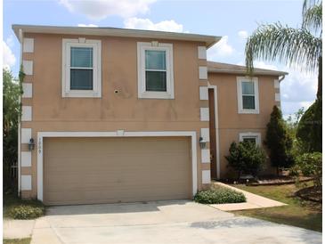 Two-story home featuring an attached two-car garage, neutral stucco siding, and decorative white trim at 1009 Ronlin St, Haines City, FL 33844