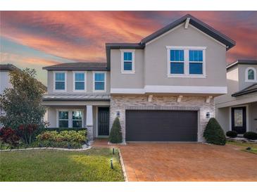 Charming two-story home with stone accents, manicured landscaping, and a brick driveway at 3310 Stonewyck St, Orlando, FL 32824
