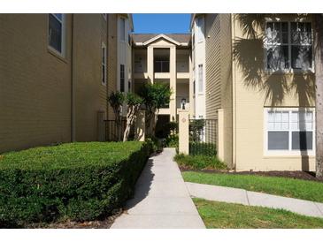Well-maintained exterior view of the apartment buildings with green shrubbery and concrete walkway at 413 Summit Ridge Pl # 215, Longwood, FL 32779