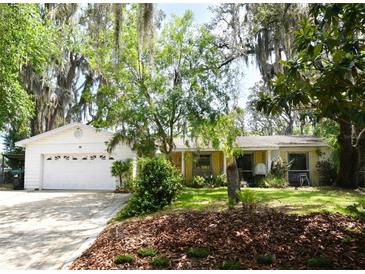 Charming home featuring a spacious front yard with mature trees and an attached two-car garage at 6105 Lost Tree Court, Orlando, FL 32808