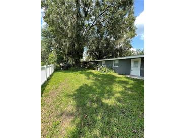 Spacious backyard featuring mature trees, a well-kept lawn and a white picket fence at 732 Trenton Rd, Lakeland, FL 33815