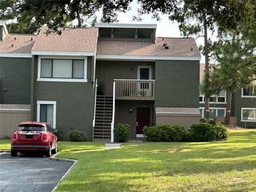 Charming two-story condo with lush green lawn, exterior staircase, and a parking space at 5964 Peregrine Ave # C02, Orlando, FL 32819