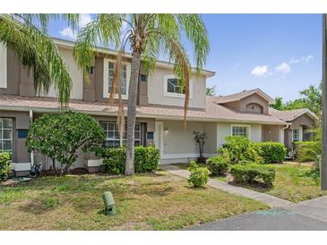 Charming townhouse exterior with tropical landscaping and a well-maintained lawn on a sunny day at 14820 Laguna Beach Cir, Orlando, FL 32824