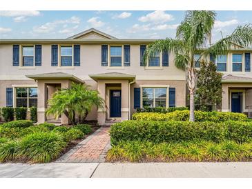 Charming townhouse featuring a well-maintained lawn, blue shutters, and a brick walkway at 16162 Arbor Crest Aly, Winter Garden, FL 34787