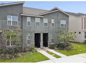 Modern townhome exterior featuring a stone facade, neutral stucco, and well manicured landscaping at 1632 Tropical Palms Circle, Kissimmee, FL 34747
