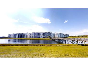 Modern condo complex with pond views and a wooden bridge walkway on a clear, sunny day at 3150 Paradox Cir # 102, Kissimmee, FL 34746
