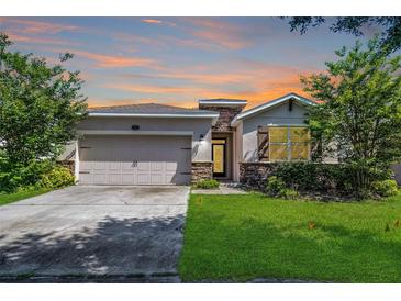 Charming single-story home with a well-manicured lawn and attached two-car garage, set against a colorful sunset sky at 405 E Freesia Ct, Deland, FL 32724
