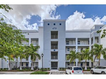 Exterior of a modern condo building with palm trees and well-manicured landscaping on a partly cloudy day at 4731 Clock Tower Dr # 105, Kissimmee, FL 34746