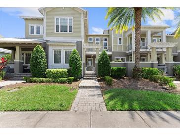 Inviting townhome with manicured landscaping, lush green lawn, and a stone pathway leading to the front entrance at 8436 Tavistock Lakes Boulevard, Orlando, FL 32827