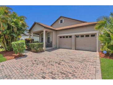 Charming home with a well-manicured lawn, brick paved driveway, neutral paint, shutters, and an attached garage at 9836 Lake District Ln, Orlando, FL 32832