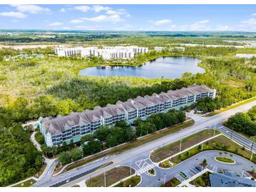 Stunning aerial view of the condo building complex featuring a serene lake and lush green surroundings at 14200 Avalon Rd # 409, Winter Garden, FL 34787
