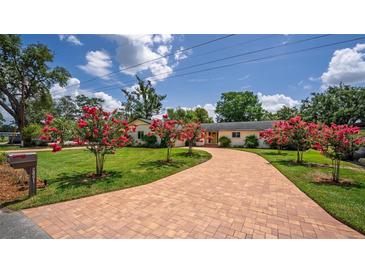 Well-manicured lawn leads to the charming front of the home with blooming crape myrtle trees at 2491 Island Dr, Longwood, FL 32779