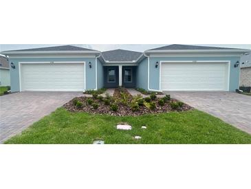 Charming attached villa featuring an attached two-car garage, landscaped yard, and brick paver driveway at 5158 Gardenrow Dr, St Cloud, FL 34772