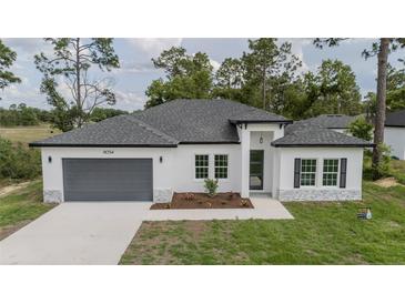 Charming single-story home features a gray garage door, white exterior, and well-maintained front yard at 6054 Sw 154Th Place Rd, Ocala, FL 34473