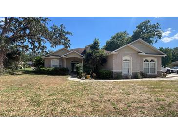 Charming home featuring tan stucco, arched windows, and a well-manicured lawn at 6438 Bristol Oaks Dr, Lakeland, FL 33811