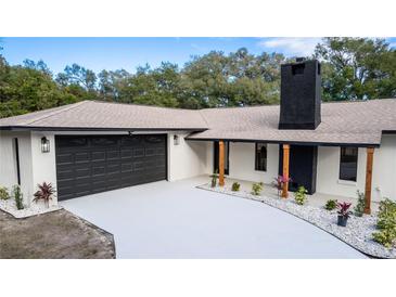 Charming home featuring a two-car garage, black trim accents, and a brick chimney at 817 Helen Ave, Deland, FL 32720