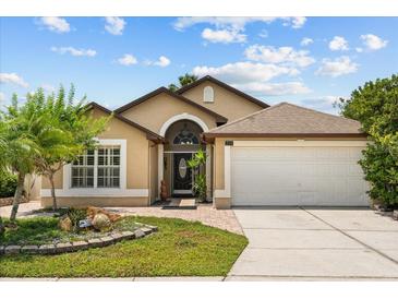 Charming single-story home featuring a two-car garage, well-manicured lawn, and beautifully landscaped front yard at 219 Old Mill Cir, Kissimmee, FL 34746